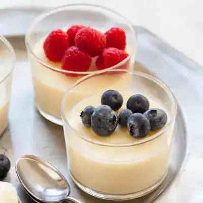 Creamy vanilla panna cotta with fresh raspberries and blueberries, perfect for dessert lovers.
