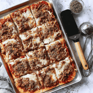 Savory homemade pizza with ground beef, cheese, and herbs in a baking sheet. Perfect for family dinners and parties.