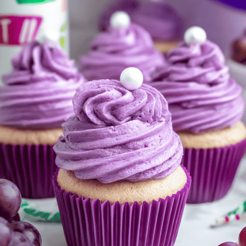 Violet grape cupcakes with purple frosting and white pearl decorations.
