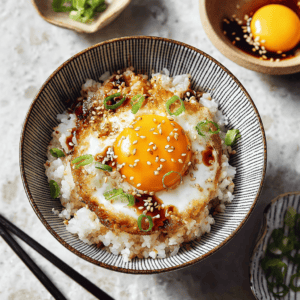 Steamed rice bowl topped with fried egg, green onions, sesame seeds, and soy sauce.