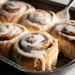 Cinnamon rolls with white icing glaze, freshly baked dessert with swirled cinnamon filling.