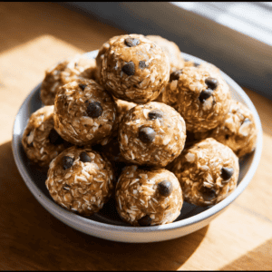 No bake energy bites with oats, peanut butter, honey, and chocolate chips on a white bowl.