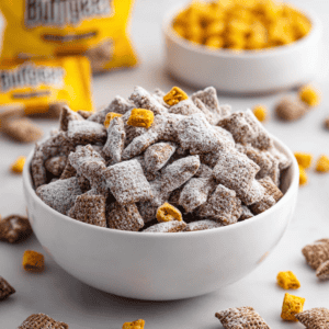 Crunchy cereal snack coated in powdered sugar with small cereal pieces on top and scattered around.