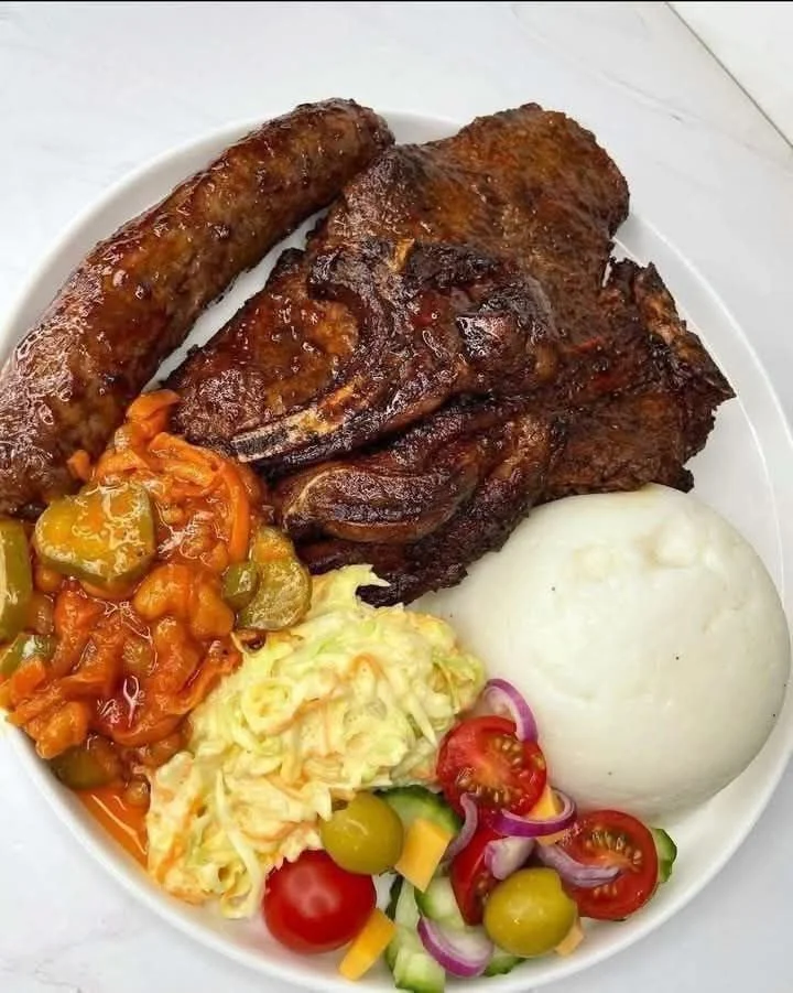 Delicious grill plate with mealie pap and chakalaka served on a wooden table.