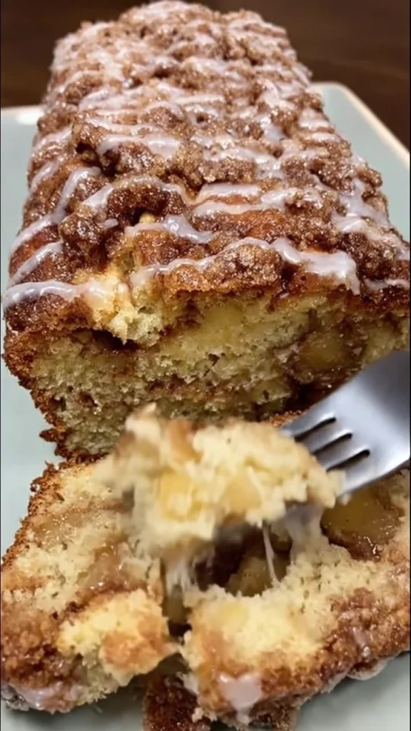 Sliced cinnamon swirl apple fritter bread with apples and cinnamon glaze